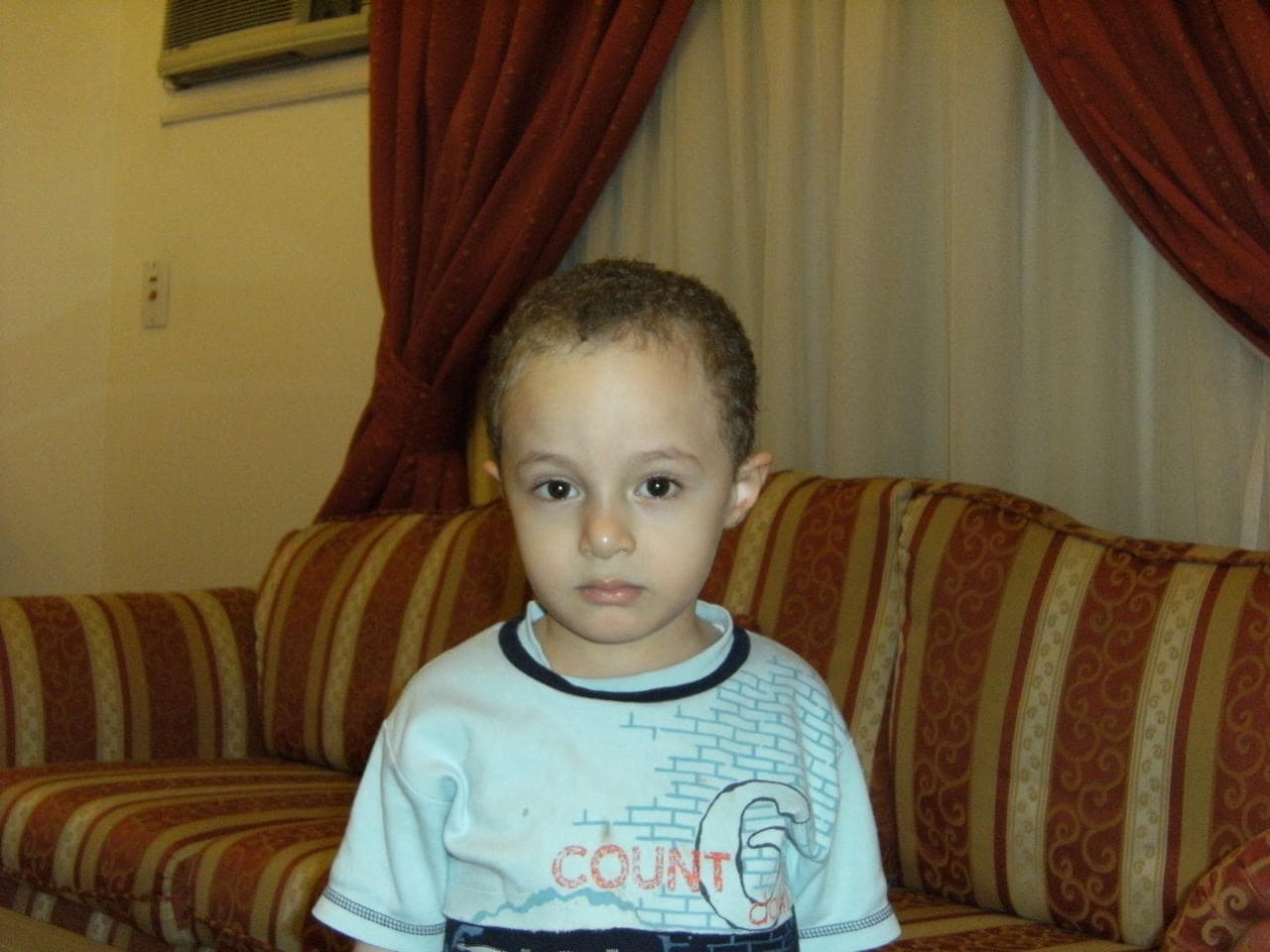 صورتي في الطفولة وأنا جالس على أريكة مزخرفة.
